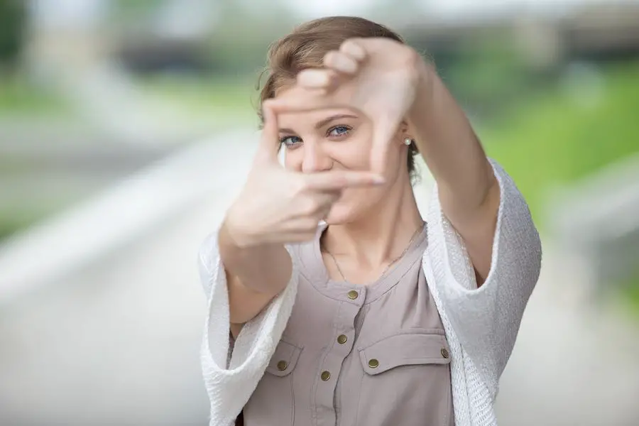 mulher imitando uma câmera com as mãos para ilustrar o que é interpretação fotográfica e sua importância para fotógrafos