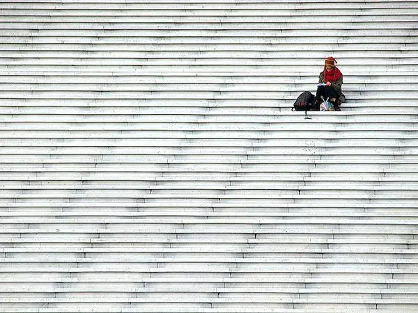 minimalismo na fotografia de uma grande escadaria branca e uma pessoa sentada no canto superior direito