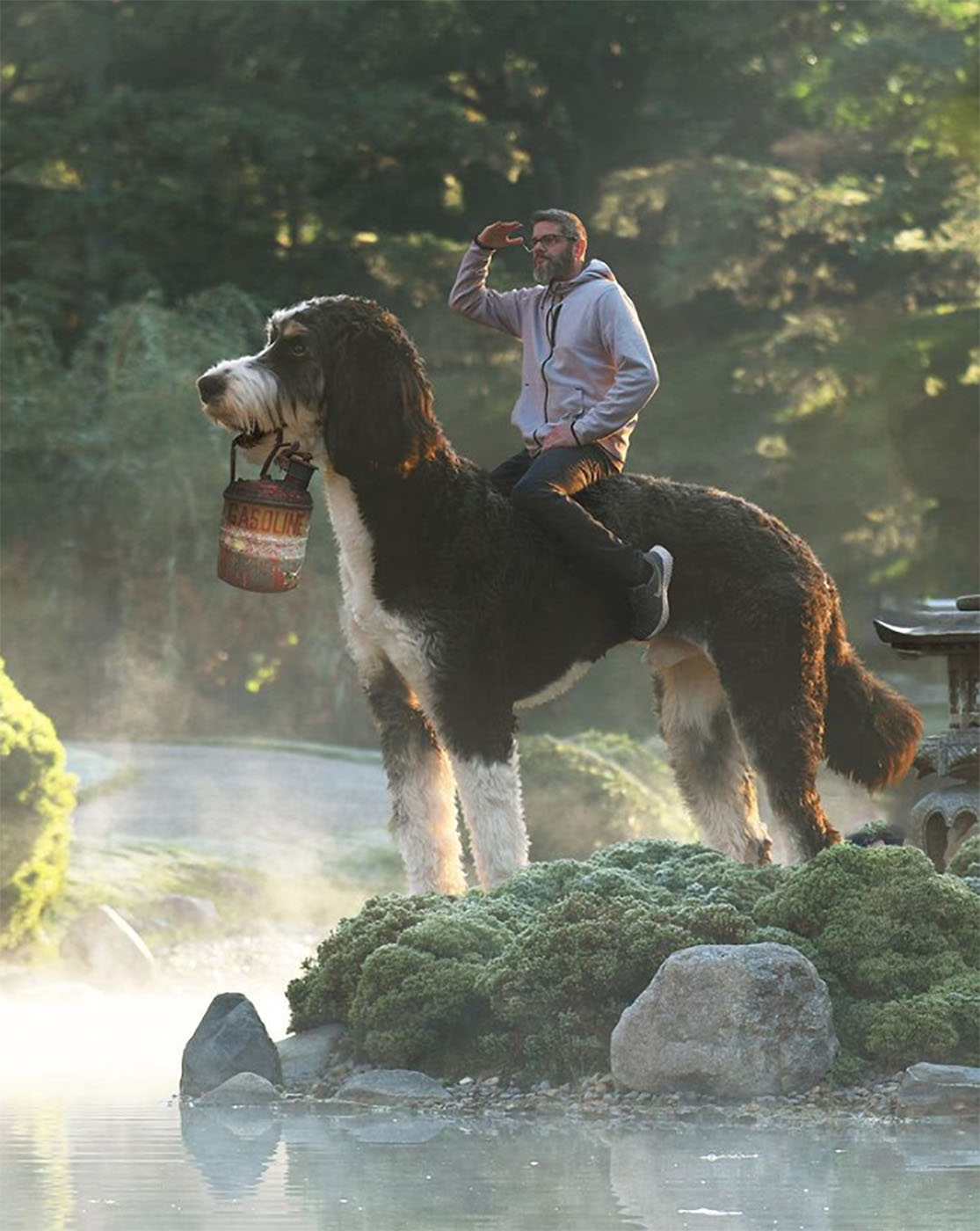 Christopher Cline procurando por algo em um lago, montando seu cachorro gigante como se fosse um cavalo
